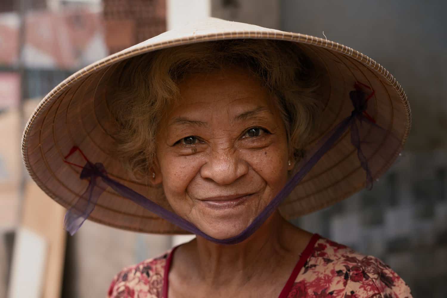 asaian woman wearing brown wicker hat. happy and smiling. content life