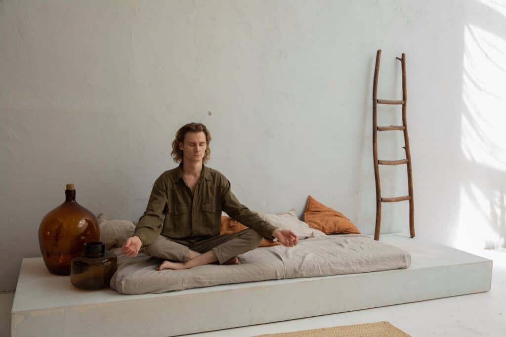 peaceful man meditating on bed in lotus pose new age spirituality 