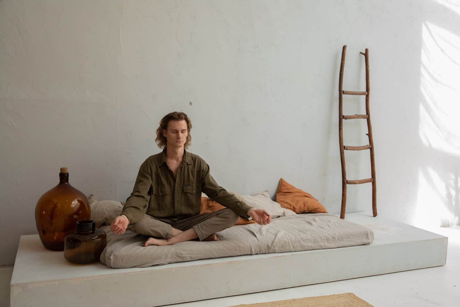 peaceful man meditating on bed in lotus pose. what is the i am that i am spiritual meaning 