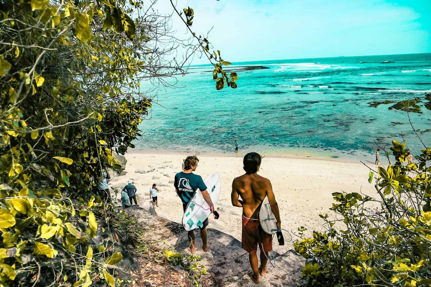 two man holding surfboards going to beach 3-week bali itinerary