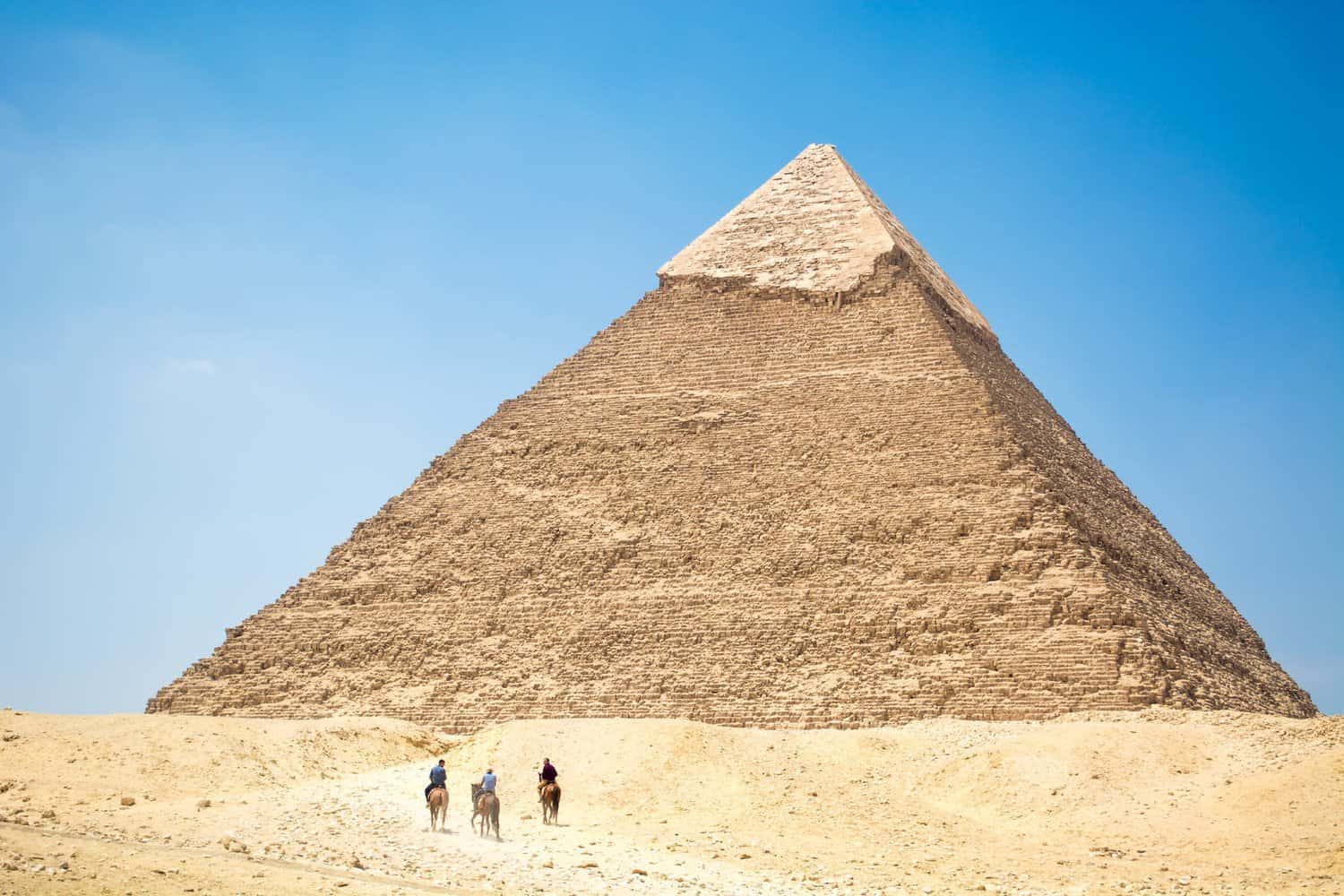 people riding a camel near pyramid under blue sky mysteries of the pyramids 