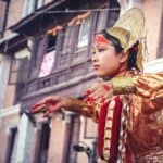 woman wearing yellow and red traditional dress dancing near building