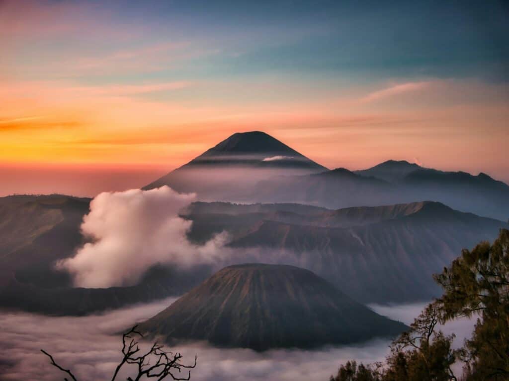sunrise over colcano and hills in the foreground, pink and orange. east java itinerary mount bromo
