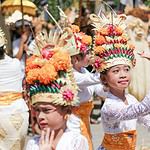 woman in white lace dress with yellow and red flower headdress. bali vs thailand