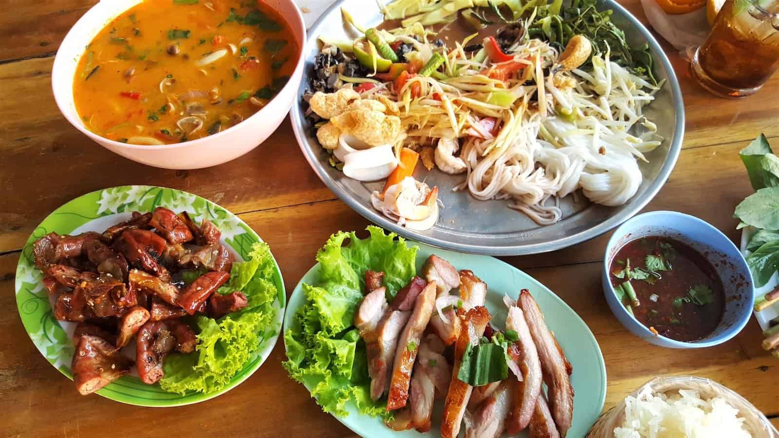 noodles with vegetables near meat with cabbage and stewed food in bowl. bali vs thailand cuisine