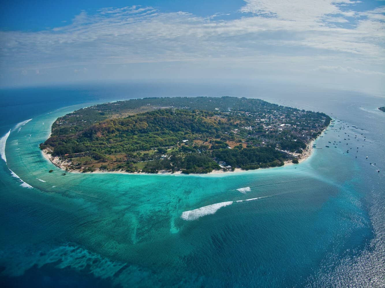 green and brown island under blue sky during daytime gili islands bali vs thailand