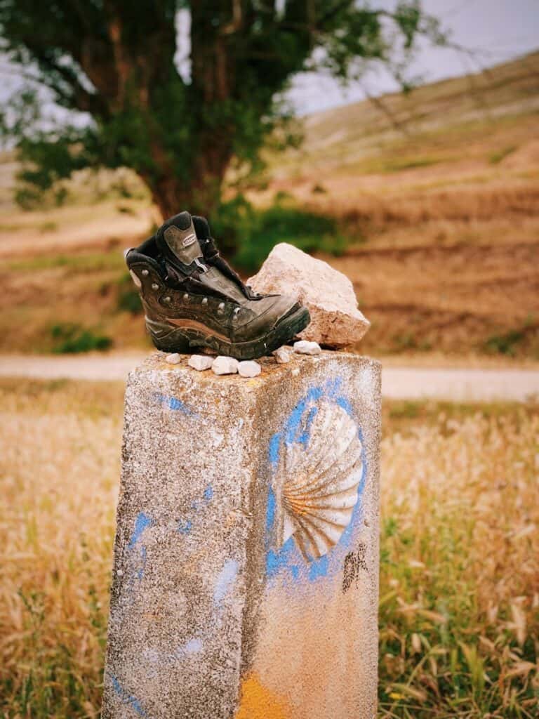 black leather shoe beside stone major pilgrimage destination in spain - the camino trail